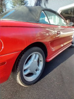1994 Mustang GT Convertible showcasing its vibrant red color and new convertible top in driveway setting.