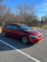 2007 Honda Civic Si sedan parked in a driveway, red color, with slight cosmetic damage.