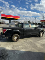 2010 Ford F-150 Supercrew truck with V8 engine parked at a gas station, showing exterior details.
