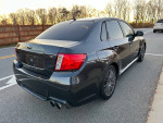 2014 Subaru Impreza WRX Sedan in excellent condition, showcasing rear view on a scenic road.