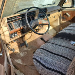 Interior of a classic 1984 Ford F250 with wood accents and a striped seat cover