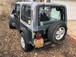 1994 Jeep Wrangler with hard and soft tops, showing rear view, located on a dirt ground