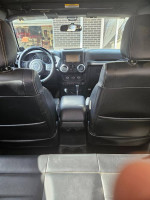 Interior view of a 2012 Jeep Rubicon showing leather seats, dashboard, and entertainment system.