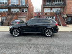 Side view of a black 2016 BMW X5 xDrive parked on a street, showcasing its sleek design and alloy wheels.