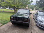 2001 Jeep Cherokee Sport in green parked in driveway, showcasing its classic design and condition.