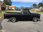 1973 Ford F-100 Short Bed truck, showcasing a sleek black exterior and custom wheels in a residential area.