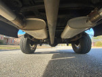Underside view of a 1973 Ford F-100 showcasing exhaust system and tires on a sunny day.