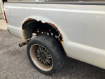 2004 Ford F350 truck with visible rust on the bed and a close-up of the rear wheel