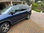 2016 Honda Pilot EXL SUV in Obsidian Blue parked in a driveway, showcasing its sleek design and spacious interior.