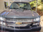 Front view of a 2003 Chevrolet Silverado 1500 with chrome grille and custom hood scoop, parked outdoors.