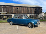 1968 BMW 1600 2002 parked in front of a rustic barn, showcasing its vintage design and modifications.