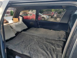 Interior of a 1993 Toyota Previa LE featuring a sleeping area with pillows and blankets, ideal for camping trips.