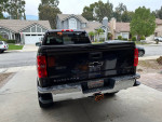 Rear view of a black 2015 Chevrolet Silverado 1500 LT 4WD with custom features parked at home.