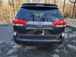 Rear view of a 2011 Toyota Sienna Limited with a clean title, parked in a wooded area.