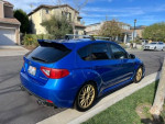 2013 Subaru Impreza WRX Hatchback in blue with gold wheels, parked on a residential street.