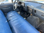 Interior view of a 1991 Ford F250 with blue seats and dashboard, showing wear and tear.