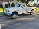Old white Ford F250 Super Duty truck with long bed parked on the street