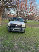 2004 Ford F350 Super Duty truck with power stroke and front grill guard, parked in a grassy area