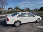 2004 Volvo S80 2.9 FWD in white, parked in a sunny area with trees, showcasing sleek design and alloy wheels.