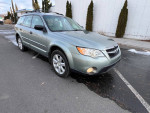 2009 Subaru Outback in silver with all-wheel drive and manual transmission, parked on a street.