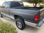 1999 Dodge Ram 1500 in gray color parked on driveway with chrome rims and tinted windows.