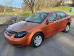 2005 Chevrolet Cobalt LS in orange, featuring sunroof, alloy wheels, and sleek design parked outdoors.