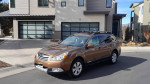 2012 Subaru Outback 2.5i AWD parked in front of a modern house, showcasing its sleek design and reliable features.