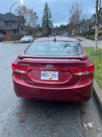 Rear view of a 2012 Hyundai Elantra parked on a residential street, showcasing its clean condition and winter tires.