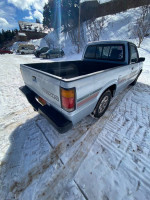 Rear view of a Mazda B2600 truck parked on snow with clear blue sky in background