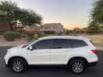 Side view of a white 2019 Honda Pilot EX SUV parked in a residential area, showcasing its sleek design.