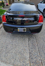 Rear view of a black 2016 Chrysler 300S with alloy wheels parked in a driveway