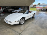 1990 Chevrolet Corvette convertible with a new top parked in a garage, showcasing its classic design and excellent condition.
