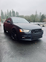 2013 Audi A4 2.0T Premium FWD parked in rainy weather showcasing sleek design and low mileage.