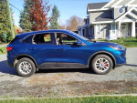 Side view of a blue 2020 Ford Escape SE FWD parked in a residential area, showcasing its design and features.