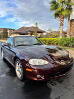 2000 Mazda Miata Special Edition in burgundy, parked outside with palm trees in the background.