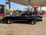 1980 Chevrolet Camaro Z28 in black, parked at a gas station, showing sleek design and clean interior.