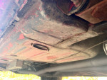 Underside view of a 1967 Ford Mustang showing original undercarriage with red paint and factory components.