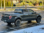 2014 Ford F150 FX4 Supercrew Cab in black parked on a snowy surface, showcasing its rugged design.