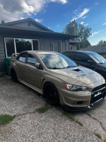 2011 Evo X GSR with performance upgrades parked in front of a house, showcasing its sporty design.