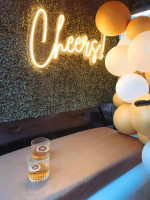 Mobile bar setup with drinks on a table and a neon 'Cheers!' sign, perfect for events and gatherings.