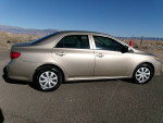Side view of a 2009 Toyota Corolla LE in gold color, showcasing its sleek design and low mileage.