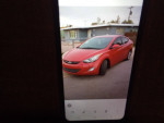 2013 Hyundai Elantra Limited sedan in red parked on the street, showcasing its sleek design and alloy wheels.