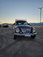 1970 VW Beetle with unique patina and new seats from a 2015 Kia Soul parked in an empty lot