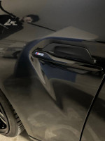 Close-up of a 2018 BMW M2 F87 badge on the car door, showcasing its unique design.
