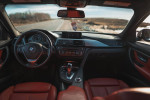 Interior view of a 2013 BMW 328i with red leather seats and modern dashboard design.