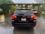 Rear view of a 2012 Subaru Outback in dark blue, parked under a shelter with rainy conditions.
