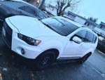 2010 Mitsubishi Outlander in white color parked, featuring new winter tires and original rims, ready for winter drives.