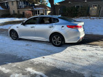 2016 Kia Optima parked on snow-covered street, silver color, clean and well-maintained, automatic transmission.