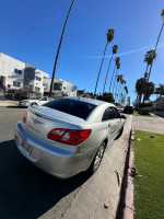 2008 Chrysler Sebring parked on a sunny street, featuring a silver exterior with body blemishes.