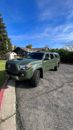 2022 Toyota Tacoma TRD Off Road 4WD in green color, parked on a street with clear blue sky.